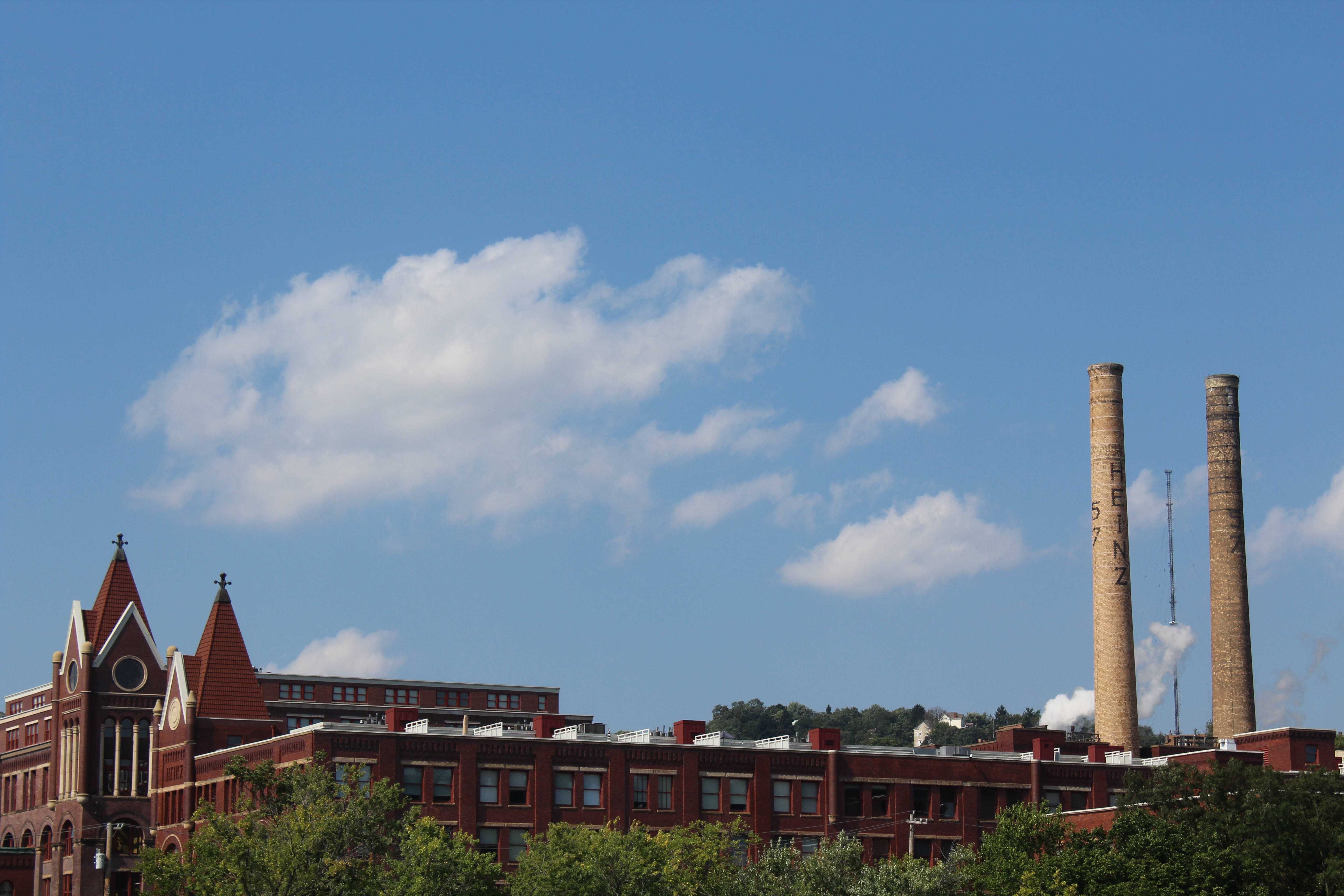 Smokestacks peek out over the top of a brick building. Taken by Jenalee Janes.